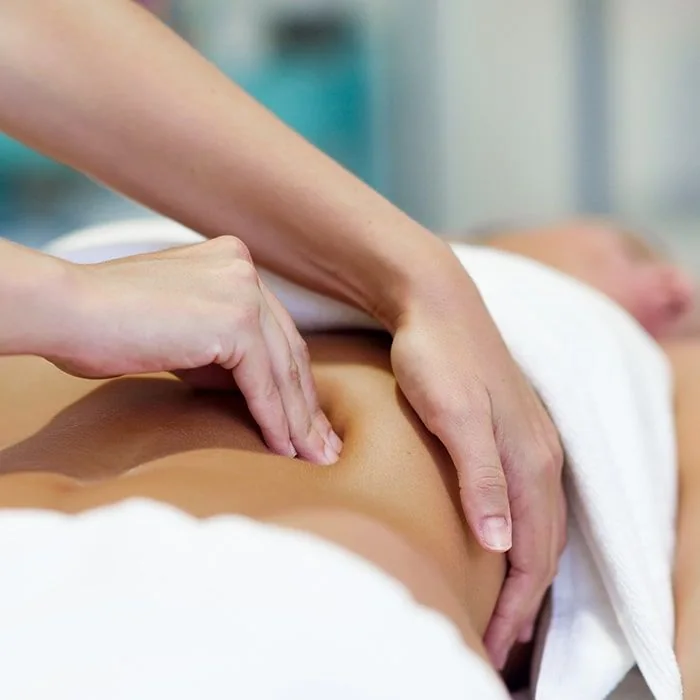 Pression douce des mains sur le ventre pendant un massage Chi Nei Tsang.