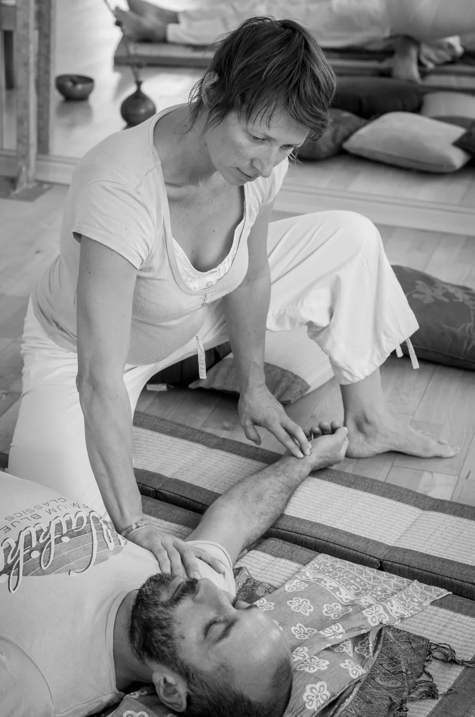 Pratique du Shiatsu sur les jambes, en noir et blanc.