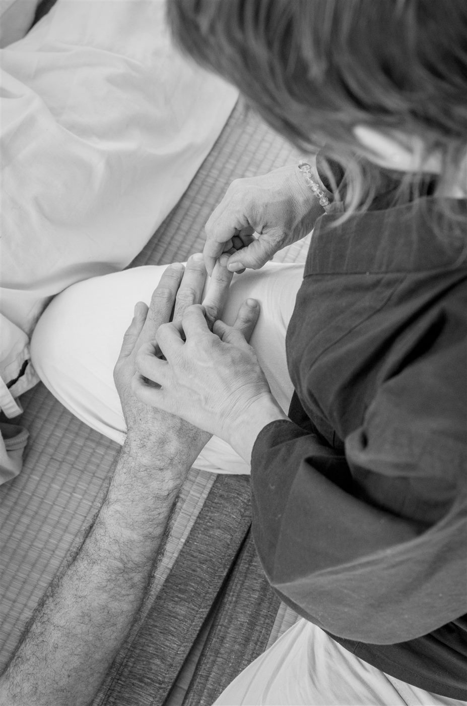Travail des mains pendant une séance de Shiatsu, en noir et blanc.